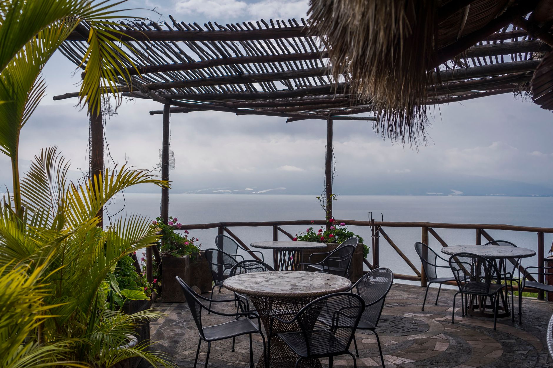 Outdoor seating and tables on a terrace overlooking the ocean coastline