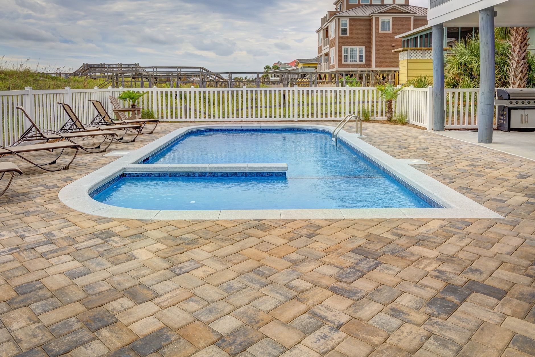 Stone pool deck patio near a fenced backyard pool